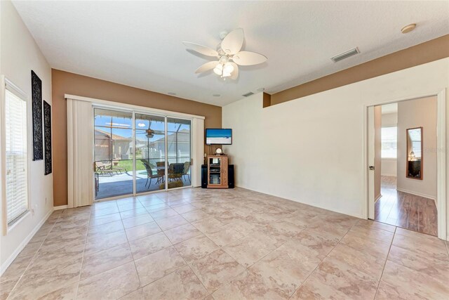 unfurnished room with a ceiling fan, visible vents, and light tile patterned floors