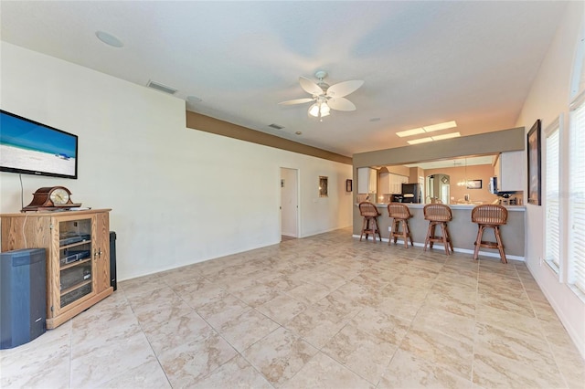 living room featuring visible vents, baseboards, ceiling fan, and a healthy amount of sunlight