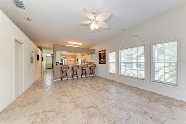 interior space featuring visible vents, a ceiling fan, baseboards, and light tile patterned floors