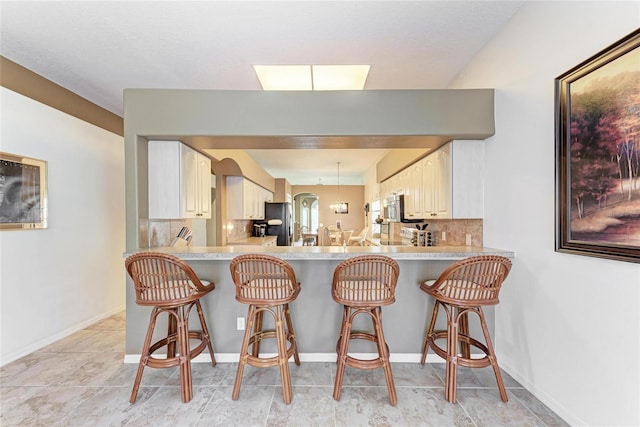 kitchen with light countertops, a peninsula, stainless steel appliances, and a breakfast bar