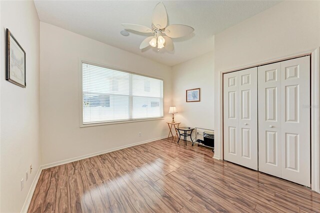 bedroom with wood finished floors, a closet, baseboards, and ceiling fan