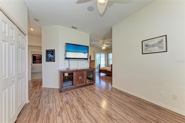 unfurnished living room featuring a ceiling fan, wood finished floors, and visible vents