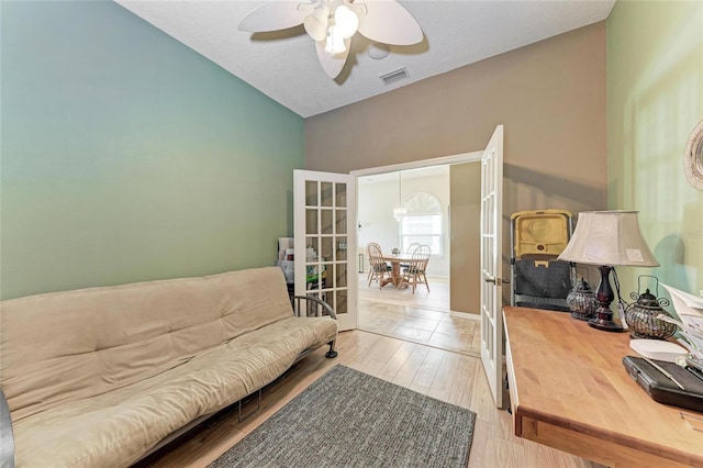 living room featuring french doors, a ceiling fan, light wood finished floors, and visible vents
