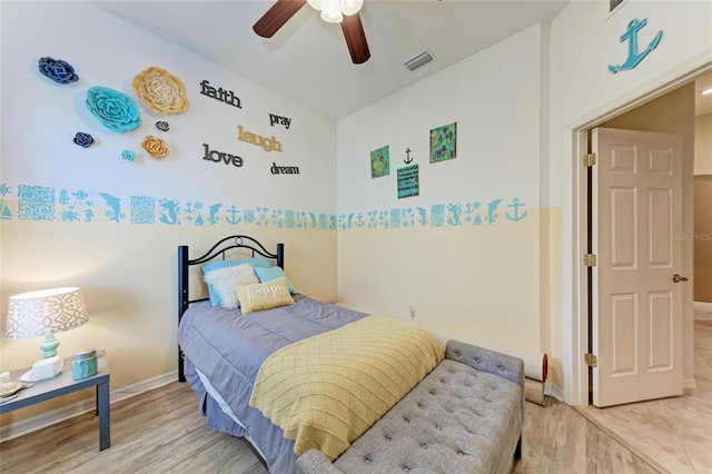 bedroom with light wood-style flooring, visible vents, baseboards, and ceiling fan