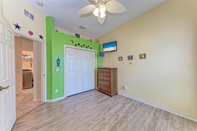 bedroom featuring light wood finished floors, visible vents, a closet, baseboards, and washer / clothes dryer