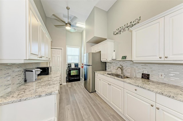 kitchen featuring freestanding refrigerator, ceiling fan, white cabinetry, and a sink