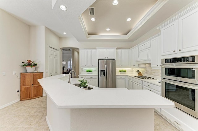 12838 Daisy Pl, Bradenton, FL 34212 - kitchen with stainless steel appliances, premium range hood, a spacious island, arched walkways, and recessed lighting