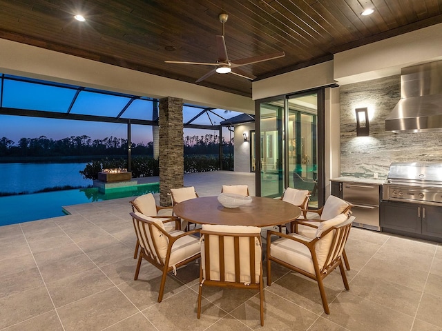 patio terrace at dusk featuring outdoor dining area, exterior kitchen, area for grilling, a ceiling fan, and an outdoor pool