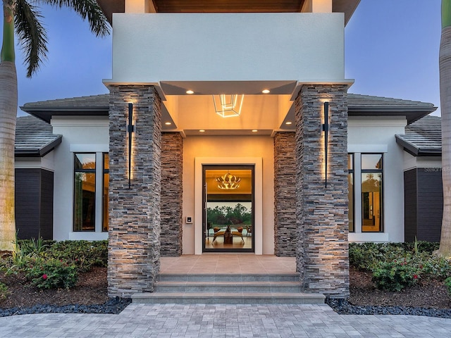 view of exterior entry featuring stone siding and stucco siding
