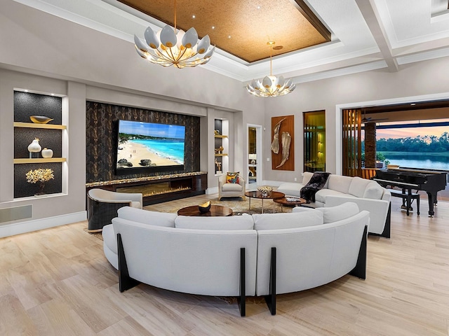 living room featuring crown molding, light wood-style flooring, a chandelier, baseboards, and built in shelves