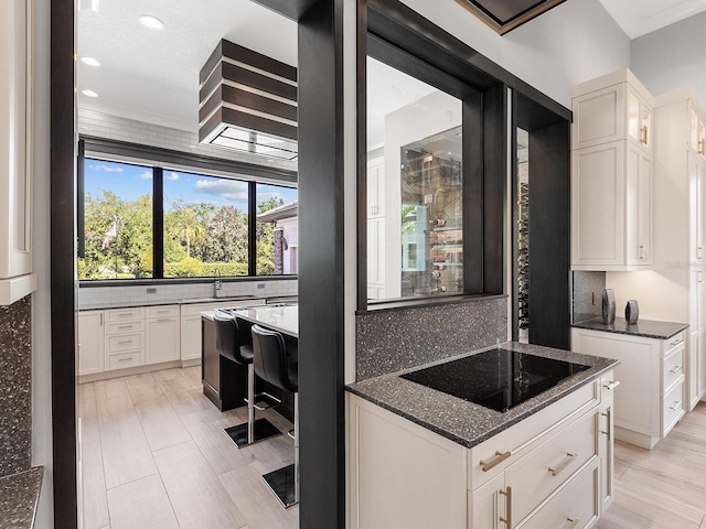 kitchen featuring dark stone countertops, tasteful backsplash, recessed lighting, black electric stovetop, and white cabinets