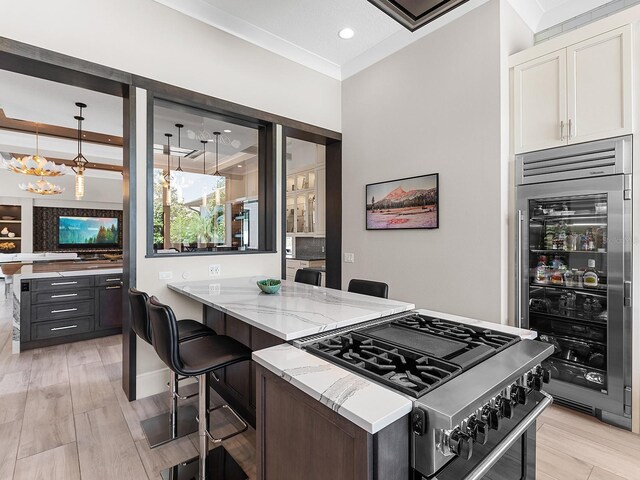 kitchen with high end stainless steel range oven, white cabinetry, a chandelier, light stone countertops, and wine cooler