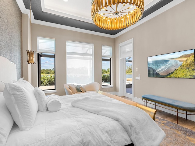 bedroom with wood finished floors, baseboards, a tray ceiling, and multiple windows