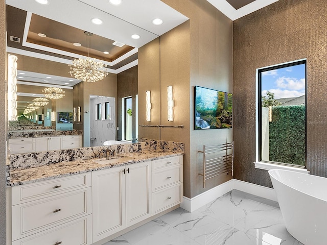 bathroom with a sink, baseboards, an inviting chandelier, a towering ceiling, and a freestanding bath