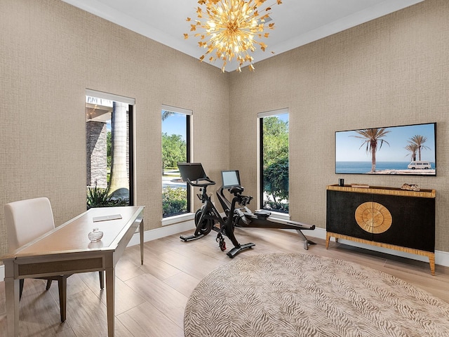 exercise area with a chandelier, light wood finished floors, and baseboards