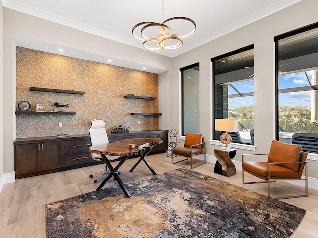 office area with baseboards, ornamental molding, a notable chandelier, and light wood-style flooring