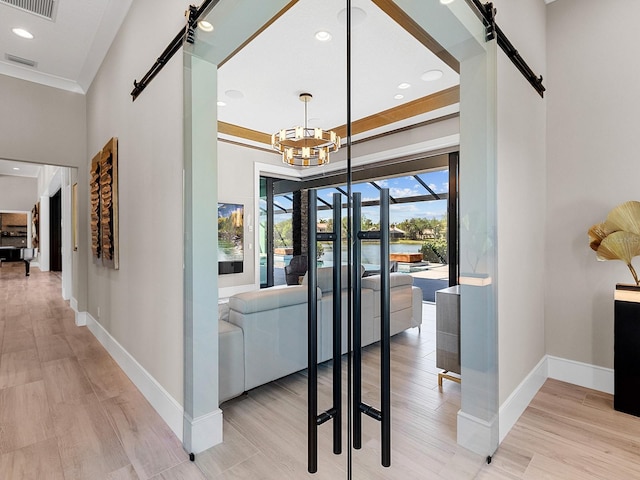 interior space featuring baseboards, a barn door, visible vents, and a notable chandelier