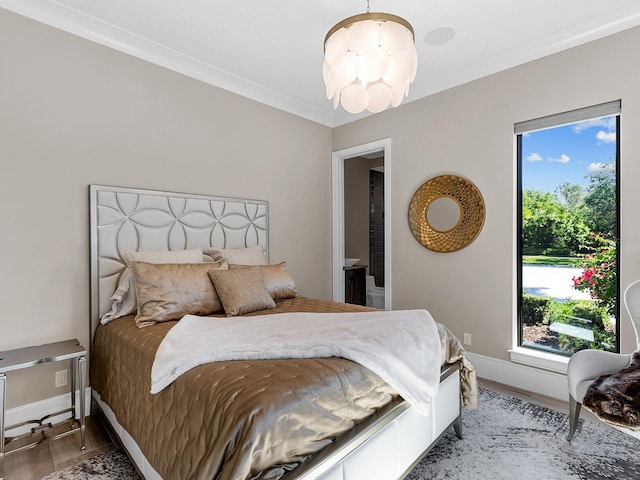 bedroom featuring ornamental molding, connected bathroom, wood finished floors, and baseboards