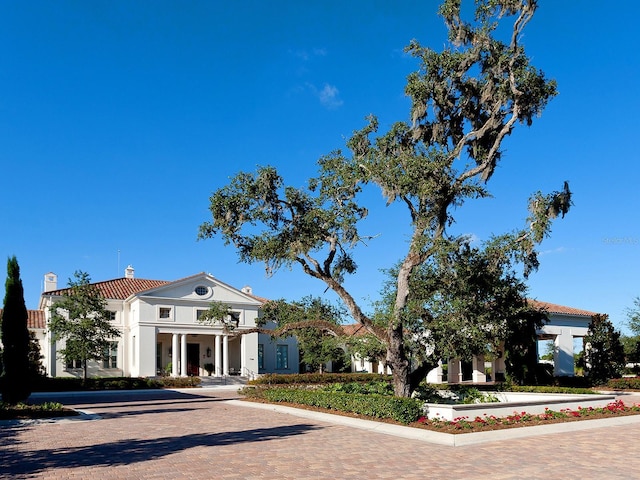 greek revival inspired property featuring a chimney and stucco siding