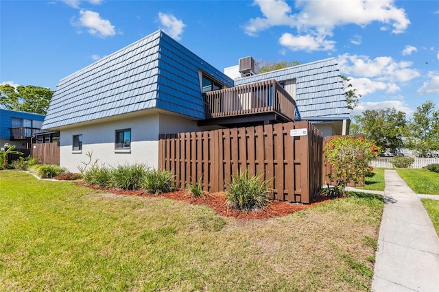 14519 Catalina Cir, Seminole, FL 33776 - view of property exterior with mansard roof, central AC, fence, a yard, and stucco siding