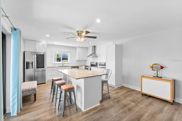 14519 Catalina Cir, Seminole, FL 33776 - kitchen featuring stainless steel appliances, wall chimney exhaust hood, a kitchen island, decorative backsplash, and a kitchen bar