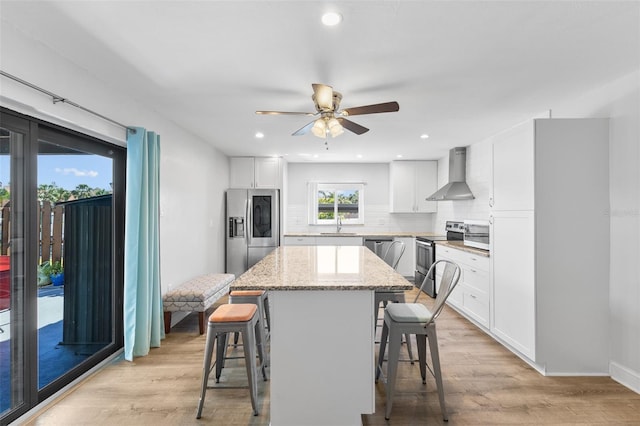 14519 Catalina Cir, Seminole, FL 33776 - kitchen featuring a kitchen breakfast bar, stainless steel appliances, a kitchen island, wall chimney exhaust hood, and decorative backsplash