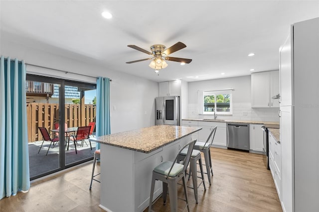14519 Catalina Cir, Seminole, FL 33776 - kitchen featuring stainless steel appliances, a kitchen breakfast bar, light wood-style flooring, a sink, and tasteful backsplash