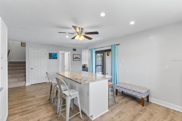 14519 Catalina Cir, Seminole, FL 33776 - kitchen featuring ceiling fan, a center island, a breakfast bar area, and light wood-style flooring