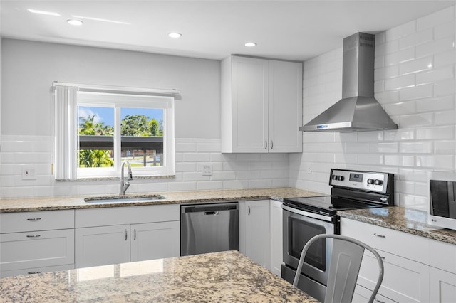 14519 Catalina Cir, Seminole, FL 33776 - kitchen with wall chimney exhaust hood, appliances with stainless steel finishes, a sink, and white cabinetry