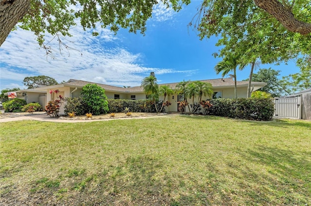 ranch-style home featuring a gate, a front lawn, and stucco siding