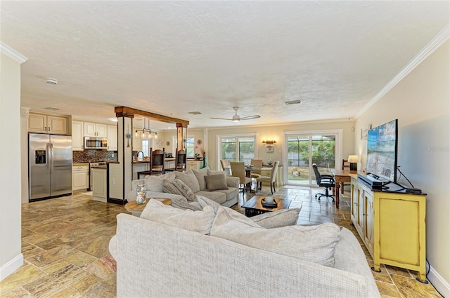 living room with ornamental molding, stone tile flooring, and ceiling fan
