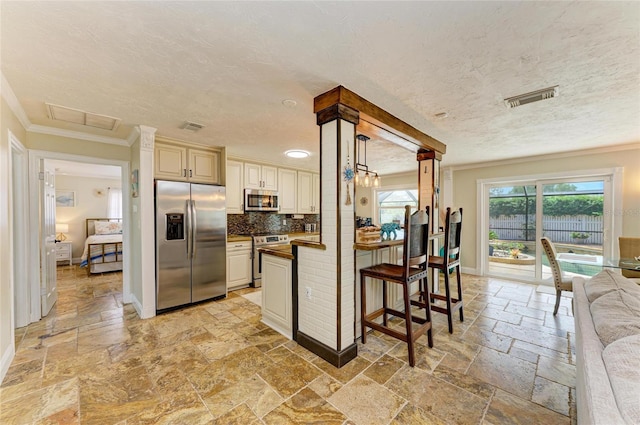 kitchen featuring stone tile floors, stainless steel appliances, dark countertops, visible vents, and crown molding