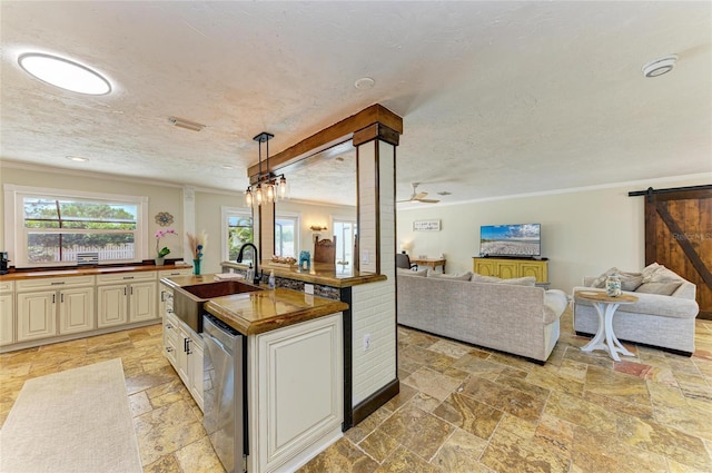 kitchen with stone tile floors, dishwasher, ornamental molding, a sink, and open floor plan