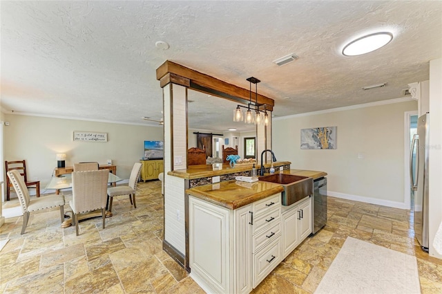 kitchen with stone tile flooring, a sink, visible vents, crown molding, and appliances with stainless steel finishes