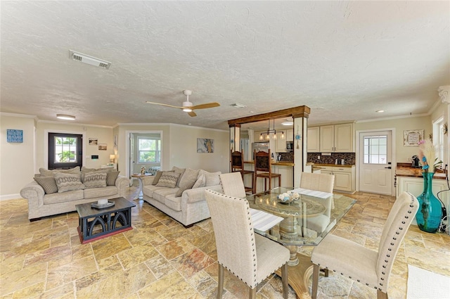 dining area with crown molding, stone tile floors, visible vents, and plenty of natural light