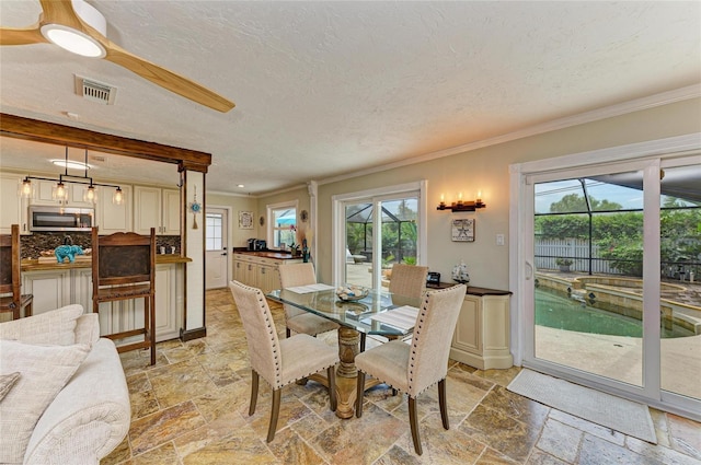 dining space with ornamental molding, stone tile flooring, a textured ceiling, and visible vents