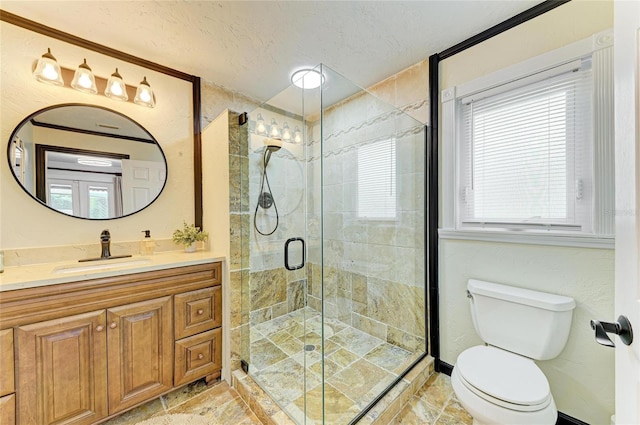 bathroom with vanity, a textured ceiling, a shower stall, and toilet