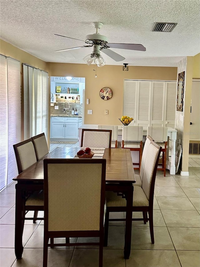 dining space with a ceiling fan, visible vents, a textured ceiling, and light tile patterned floors