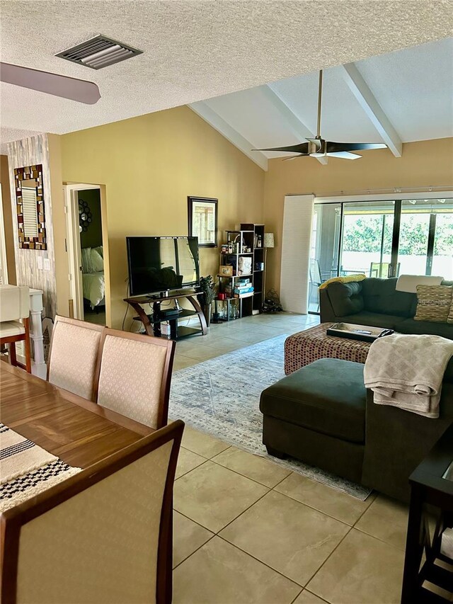 living room with a textured ceiling, vaulted ceiling with beams, visible vents, a ceiling fan, and light tile patterned floors