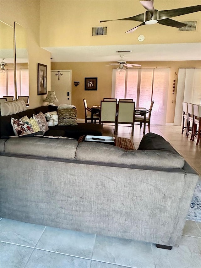 living room featuring tile patterned floors, visible vents, and ceiling fan