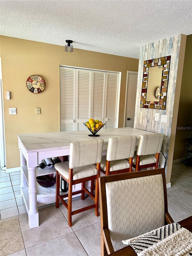 dining room featuring light tile patterned flooring, a textured ceiling, and baseboards