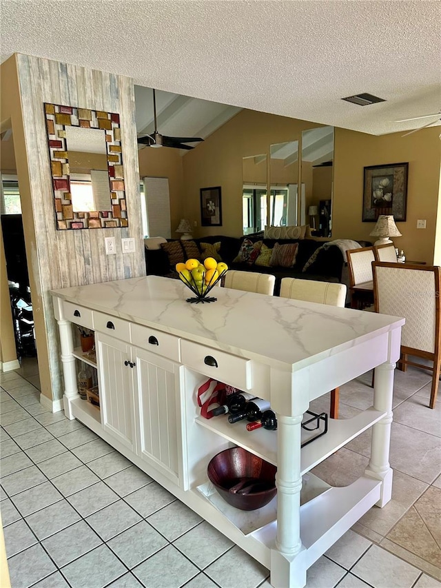 kitchen featuring open shelves, a textured ceiling, white cabinets, and light tile patterned floors