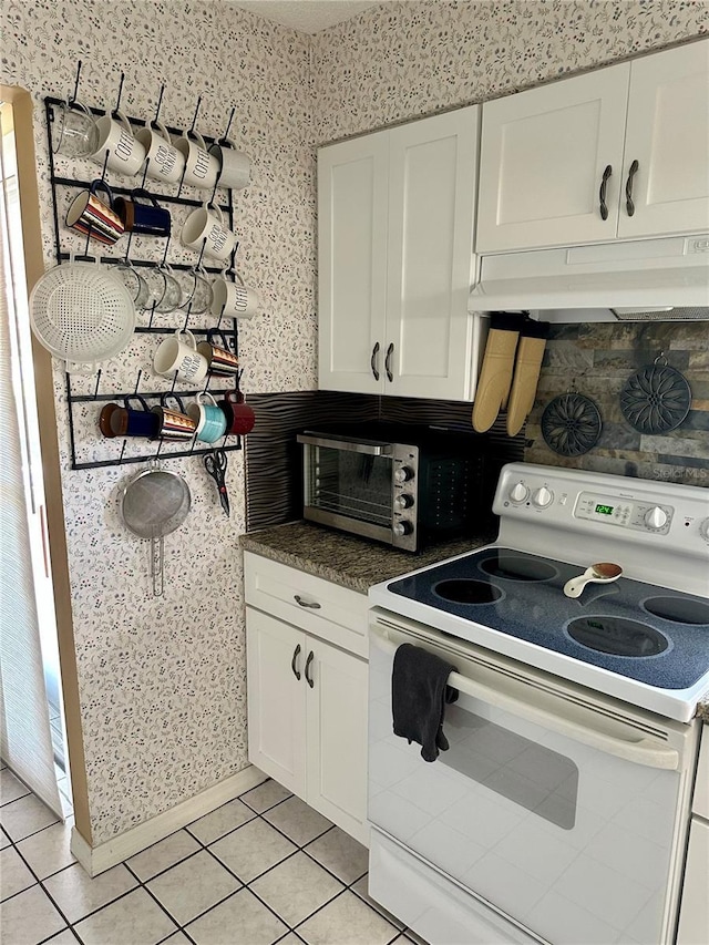 kitchen featuring white cabinetry, wallpapered walls, under cabinet range hood, white range with electric cooktop, and light tile patterned floors