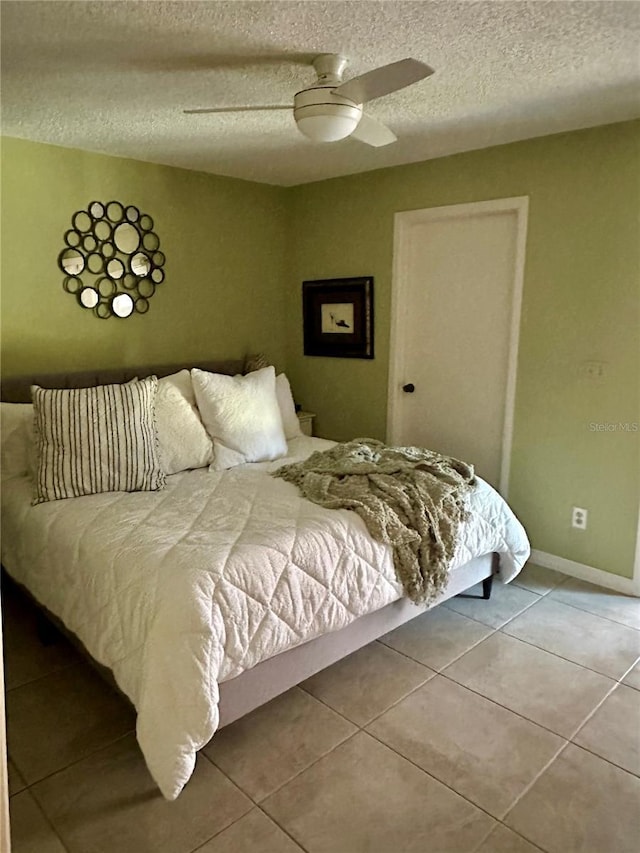 bedroom with a textured ceiling, tile patterned flooring, baseboards, and a ceiling fan