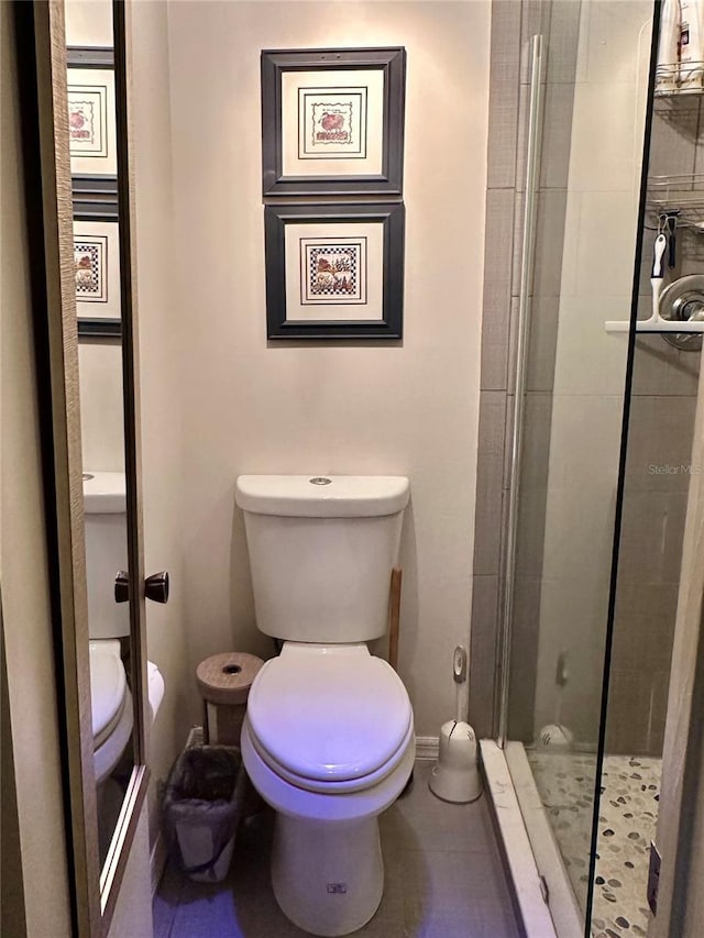 bathroom featuring baseboards, toilet, and a stall shower