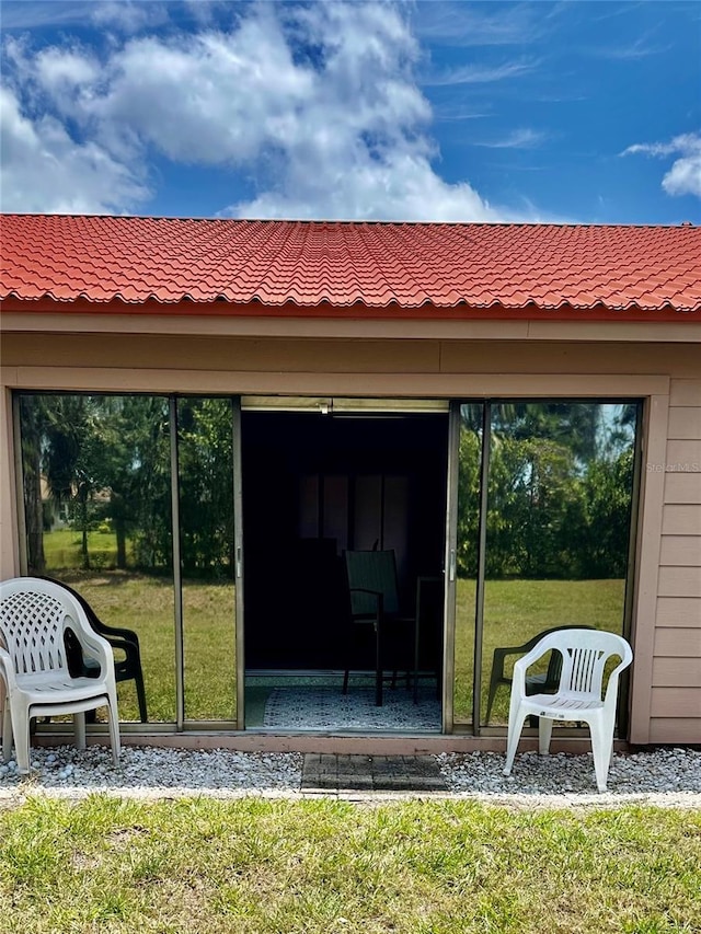 entrance to property featuring a yard and a tiled roof