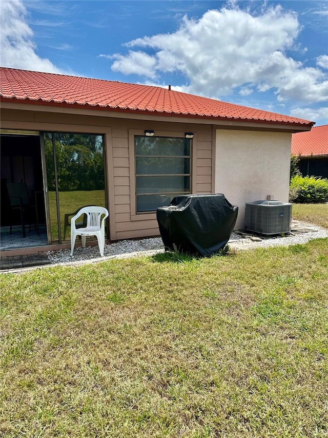 back of property with central air condition unit and a yard