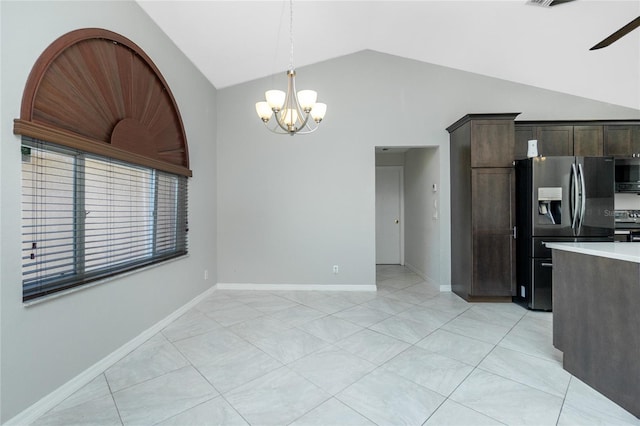 kitchen with lofted ceiling, light countertops, dark brown cabinetry, appliances with stainless steel finishes, and ceiling fan with notable chandelier