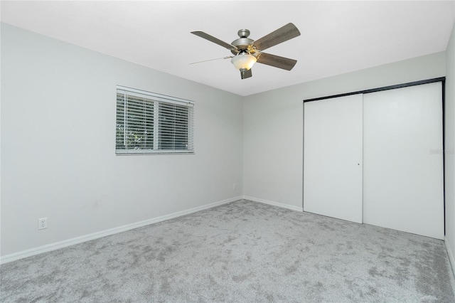 unfurnished bedroom with carpet floors, a closet, a ceiling fan, and baseboards