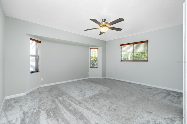 carpeted empty room featuring a ceiling fan and baseboards
